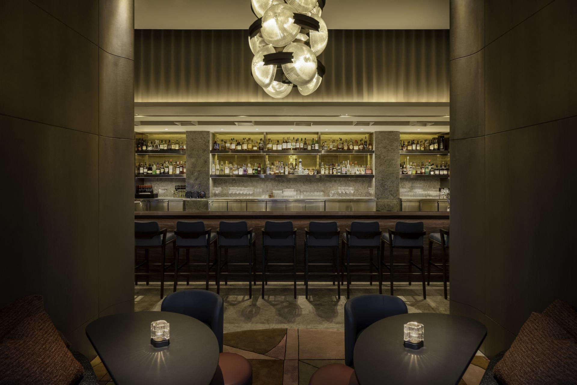 Elegant Art Deco bar interior at The Upper House, featuring stylish seating and an array of premium spirits.