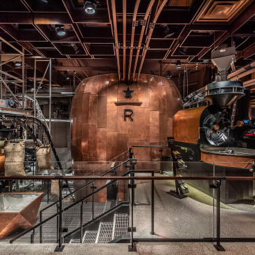 Inside the New York Starbucks Reserve Roastery, showcasing custom roasting equipment and copper decor in a modern design.