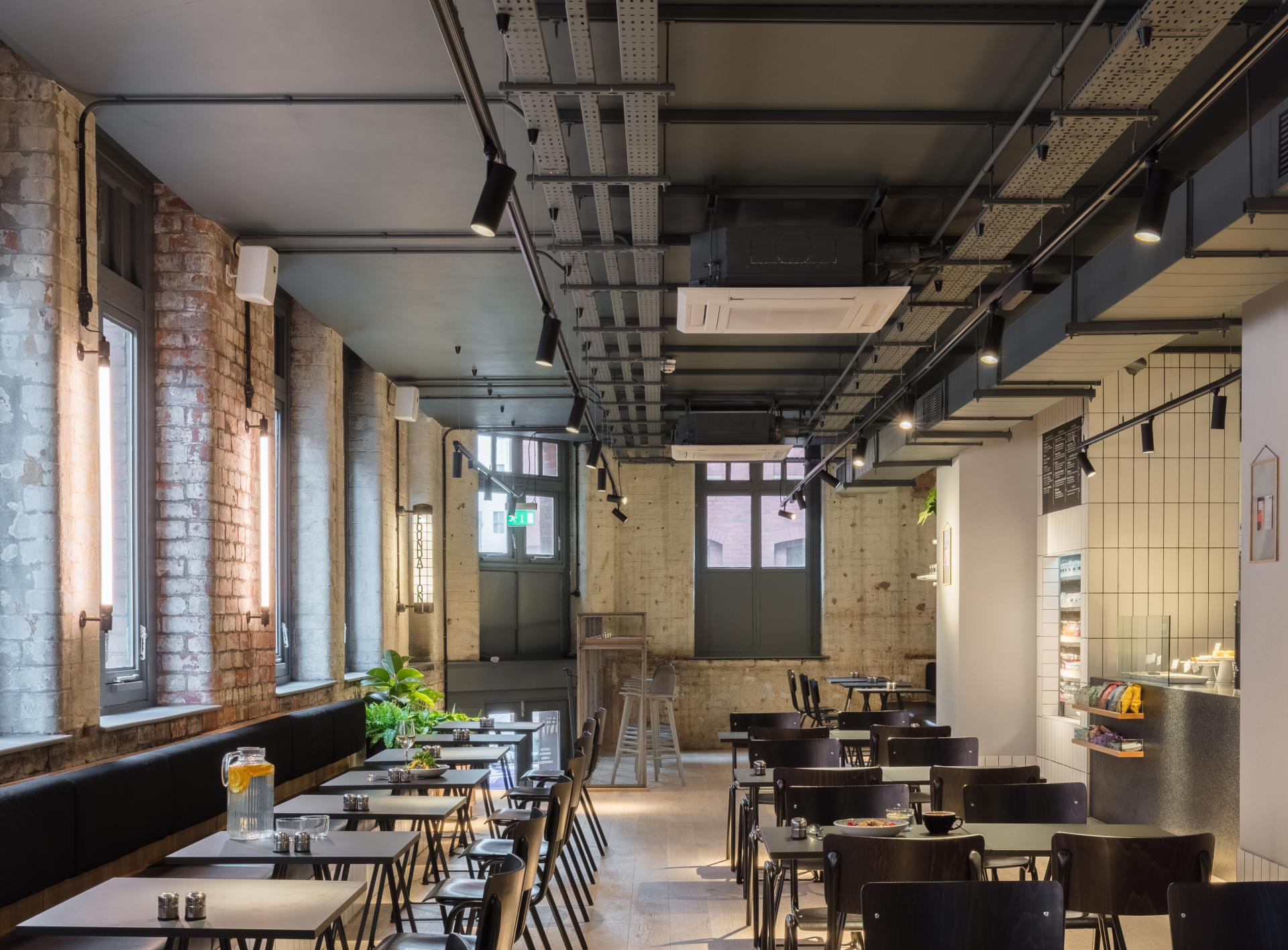 Stylish dining area in Whitworth Locke, featuring cozy seating, historic brick walls, and modern decor in Manchester's Civic Quarter.
