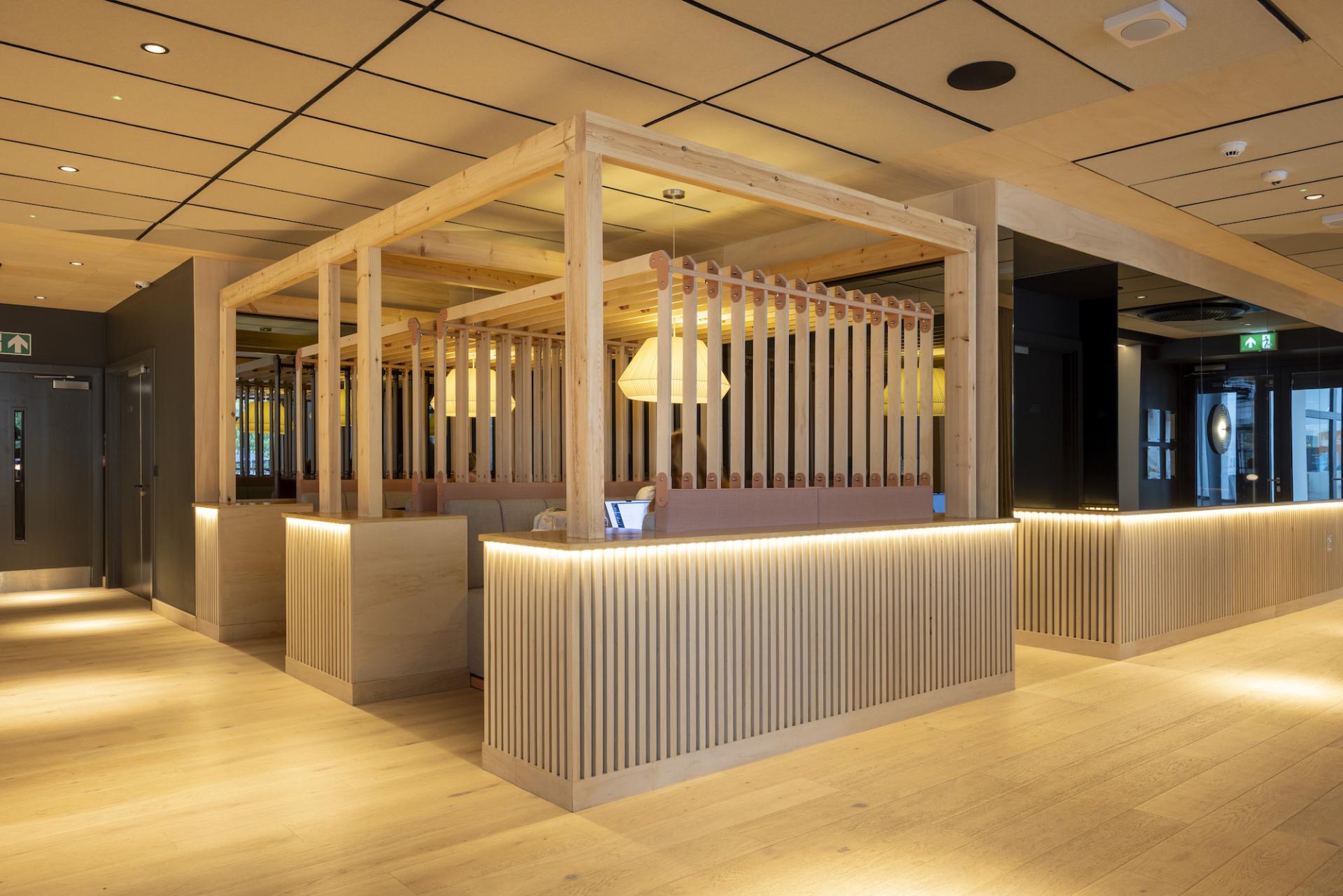 Modern interior of Junction at Manchester Central with wooden accents, glowing lights, and distinct seating arrangements designed by Up North Architects.