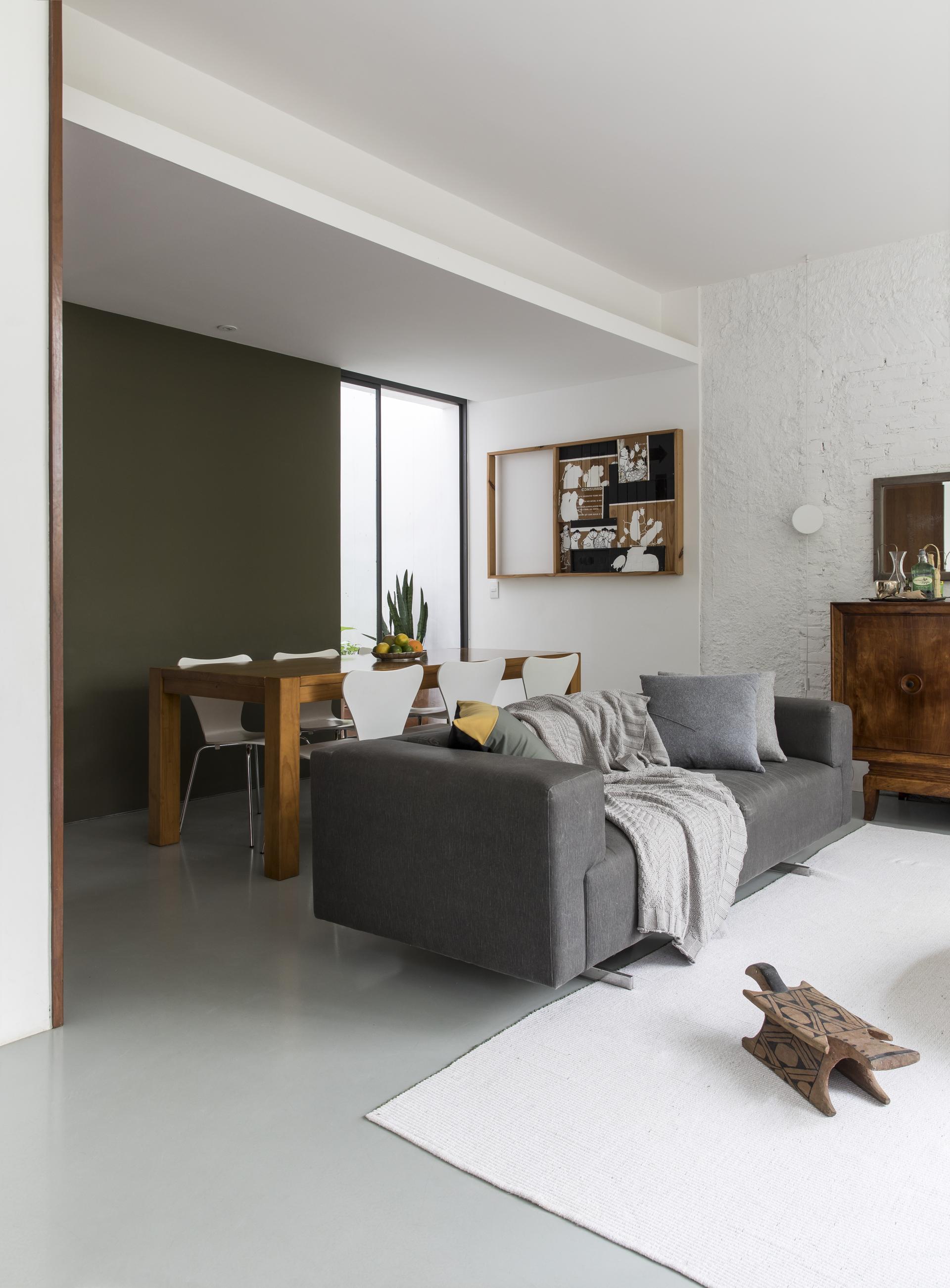 Mid-century modern living space showcasing a grey sofa, dining area, and decorative elements in a renovated São Paulo apartment.