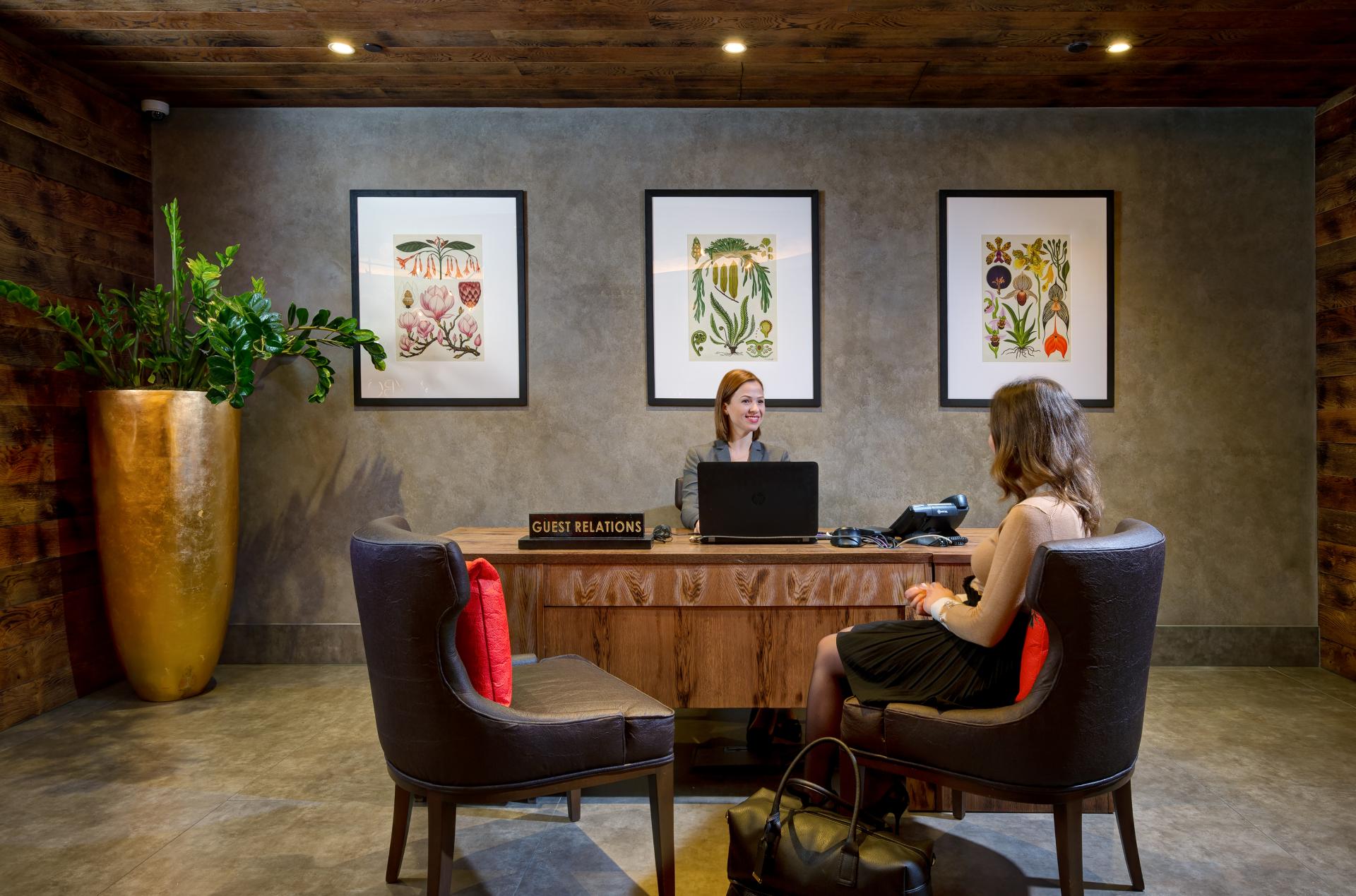 Vegan hotel suite reception featuring plant-inspired decor and a welcoming guest relations staff member.