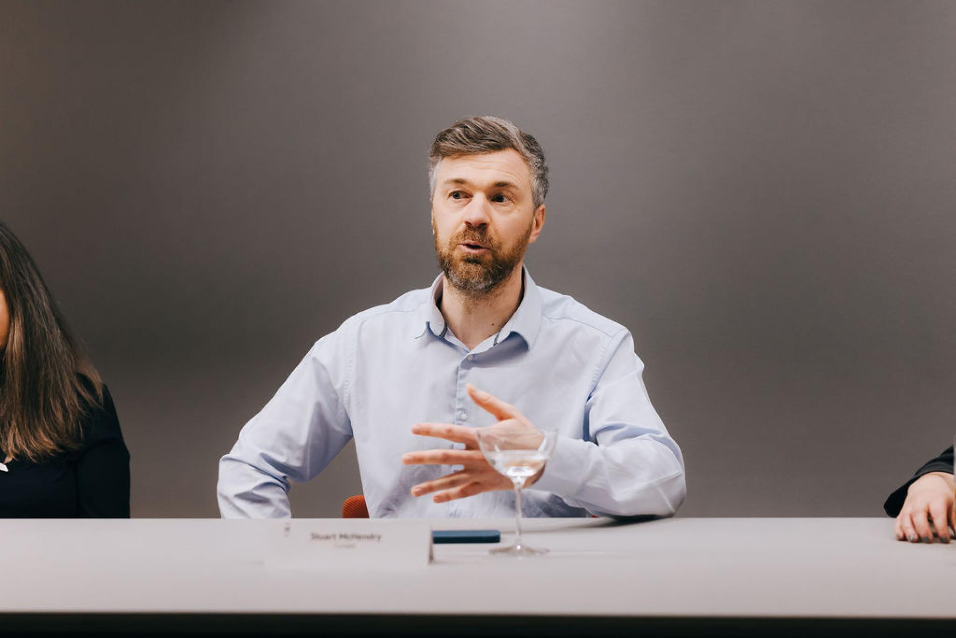 A man discusses sustainable biomaterials at a roundtable event, emphasizing their importance in modern design.