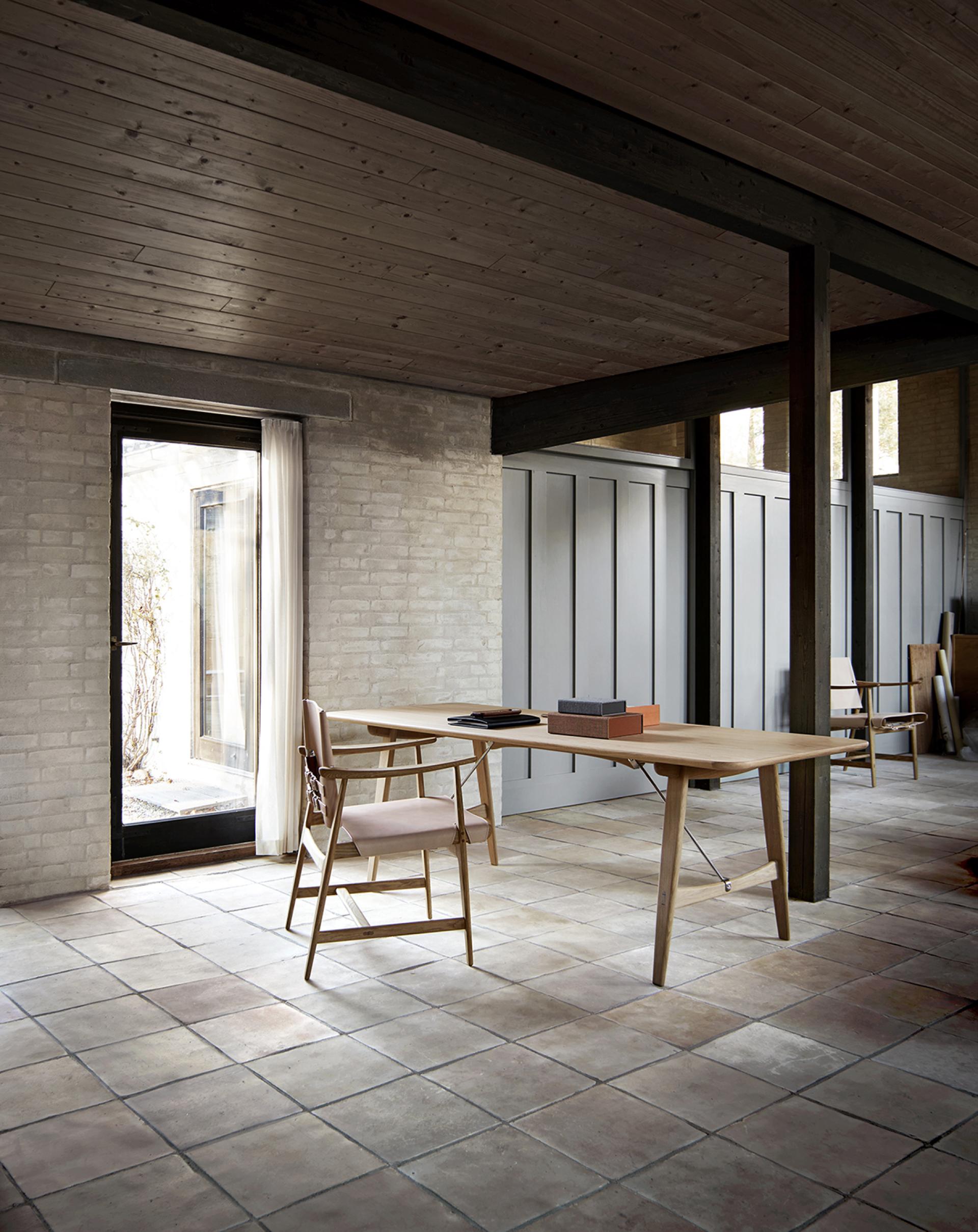 Elegant interior featuring Børge Mogensen’s Huntsman Chair beside a modern wooden table in a minimalist design setting.