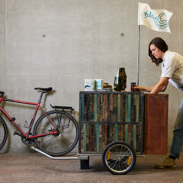 Alex Huller setting up a mobile booth for her kelp farming project, featuring a bicycle and eco-friendly displays.