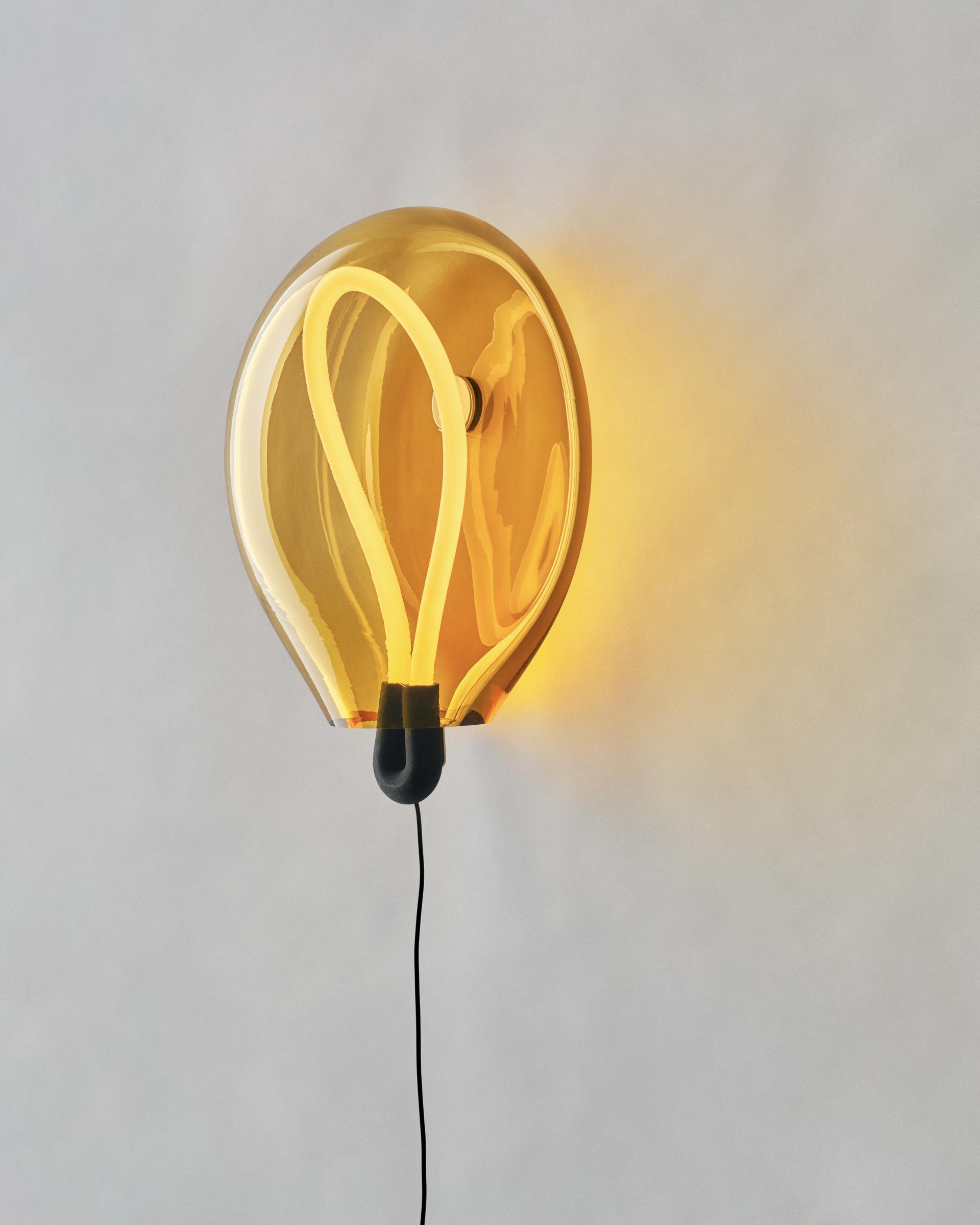 Warm amber balloon-shaped lamp with a unique neon light design, showcasing playful color palettes from Dutch Design Week 2023.
