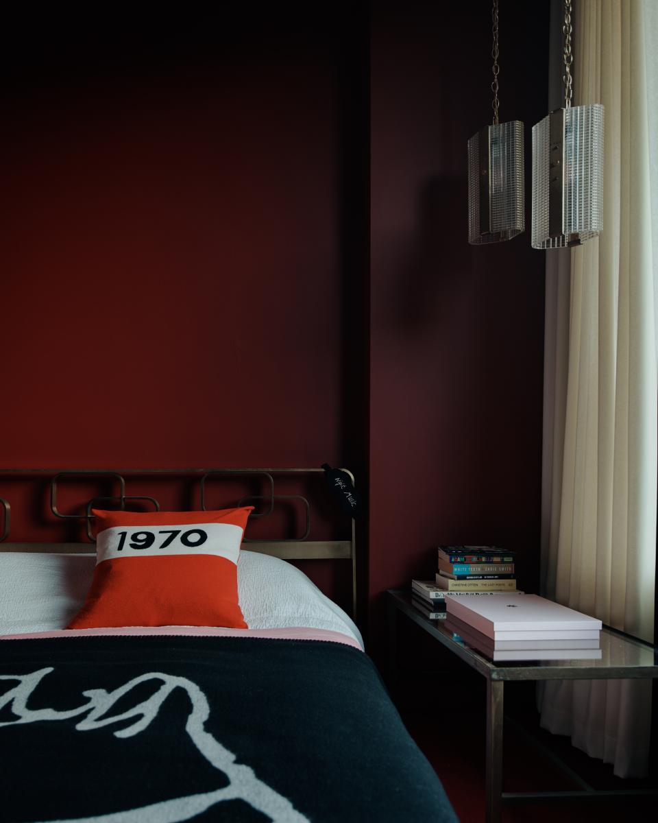 Elegant bedroom design featuring a stylish bed with bold pillows, rich colors, and contemporary decor by Bella Freud and Maria Speake.