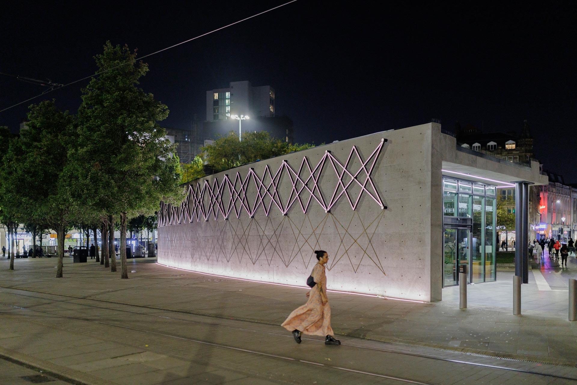 Modern Piccadilly Gardens Pavilion illuminated at night, featuring unique architectural design and surrounded by vibrant urban activity.