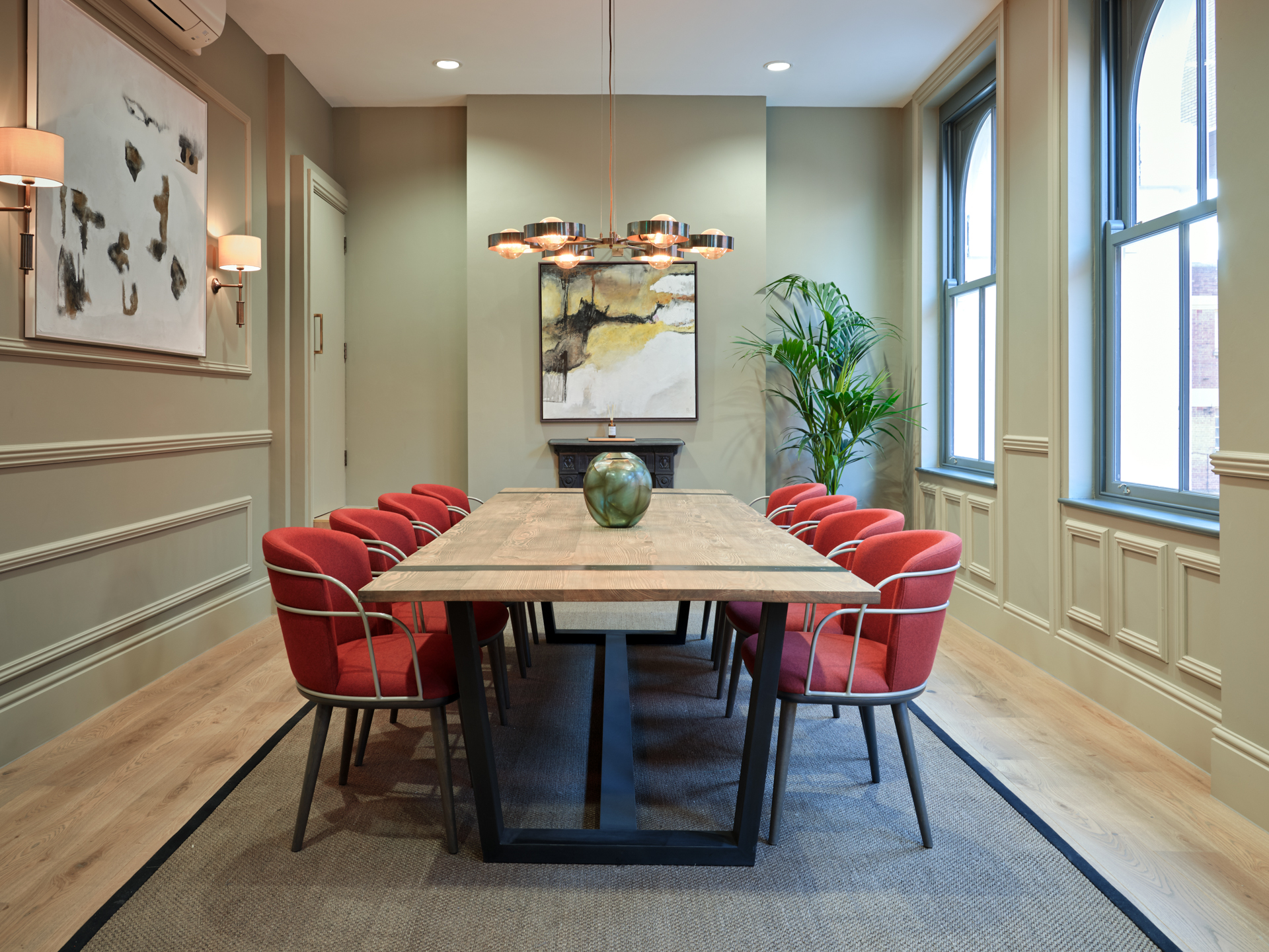 Modern conference room featuring a large wooden table and red chairs, designed to foster collaboration in urban environments.