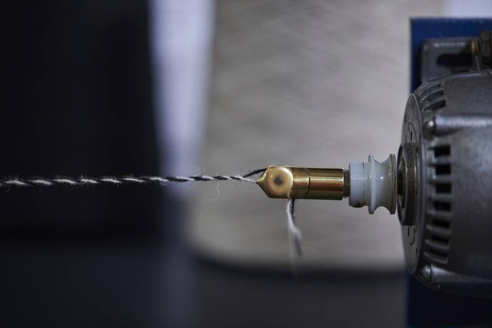 Close-up of a spinning machine component processing wool and flax fibers for Camira's Main Line Twist tweed textile.
