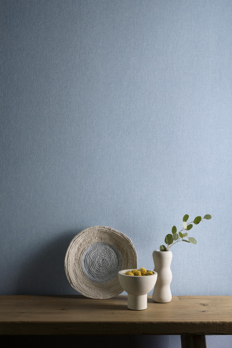 Stylish display featuring wallcovering from Arte's Flamant Honoré collection, accompanied by textured ceramics and a decorative bowl.