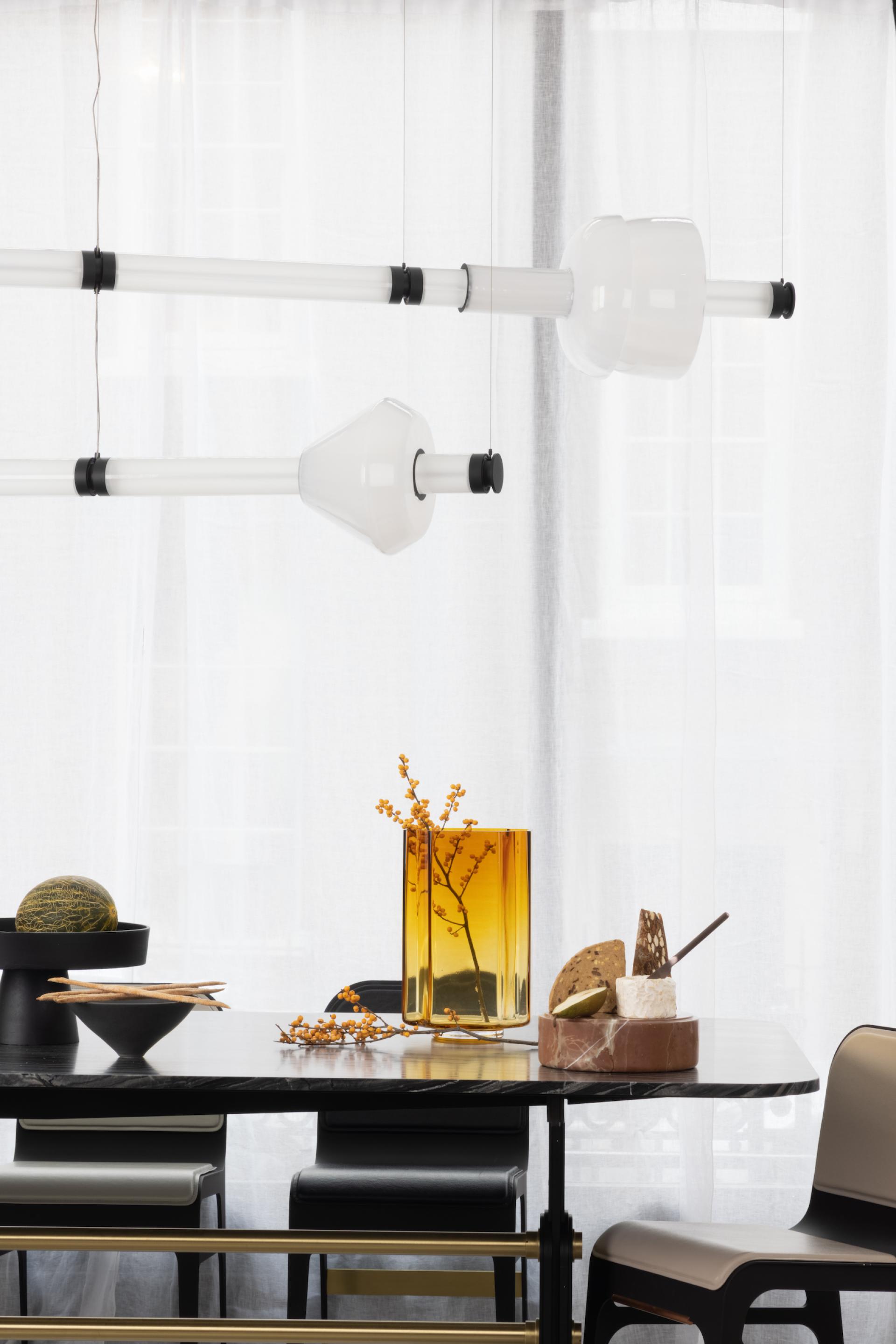 Luna Kaleido lighting fixtures hang above a stylish dining table adorned with decorative items and elegant tableware.