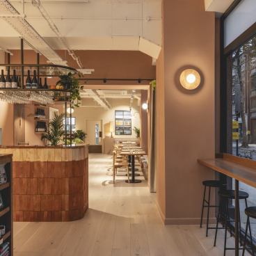 Welcoming interior of Honey & Co's deli, showcasing warm terracotta tones, wooden accents, and a stylish dining area.