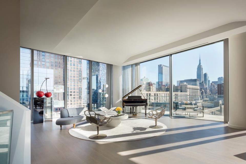 Luxurious penthouse interior by Zaha Hadid, featuring a grand piano and stunning views of the New York City skyline.