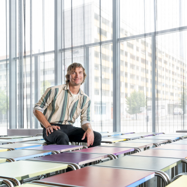 Designer Jay Gard seated on colorful B 9 tubular steel stools at the Bauhaus Museum Dessau, showcasing his limited artist’s editions.
