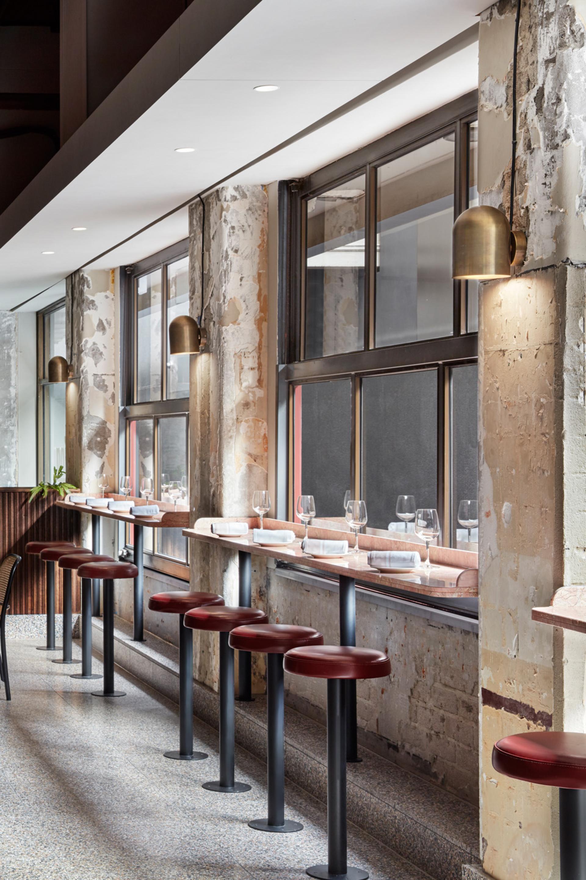 Stylish interior of Pentolina restaurant featuring red stools, marble counters, and large windows, capturing an Italian pasta bar vibe.