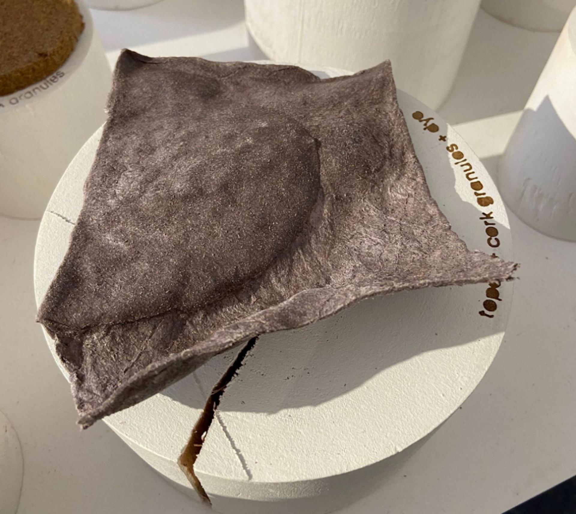 Biomaterial sample showcasing sustainable design, featuring a textured, brownish sheet placed on a circular display.