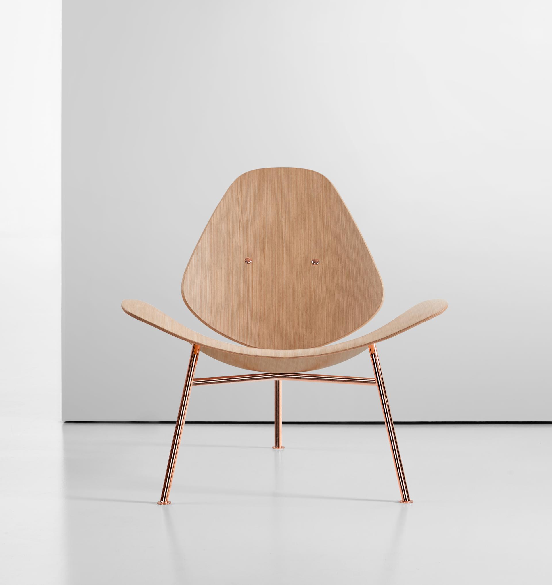 Pedersen lounge chair by Thomas Pedersen, featuring a sleek wood design and minimalist copper legs, showcased in a modern setting.