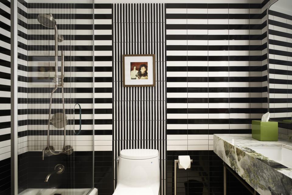 Stylish black and white striped bathroom featuring modern fixtures and decorative wall art in Park Lane New York.