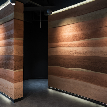 Stylish interior showcasing Clayworks' rammed earth-inspired wall finishes with natural textures and earthy color variations.