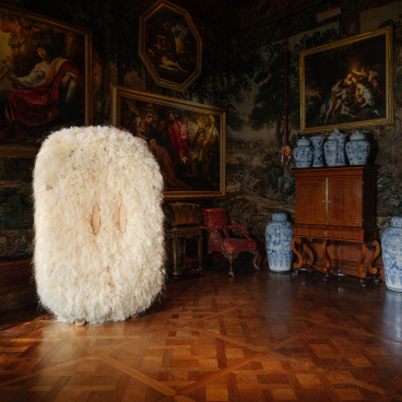 Fluffy white art piece stands in Chatsworth House's lavishly decorated room, showcasing rich heritage and materiality.