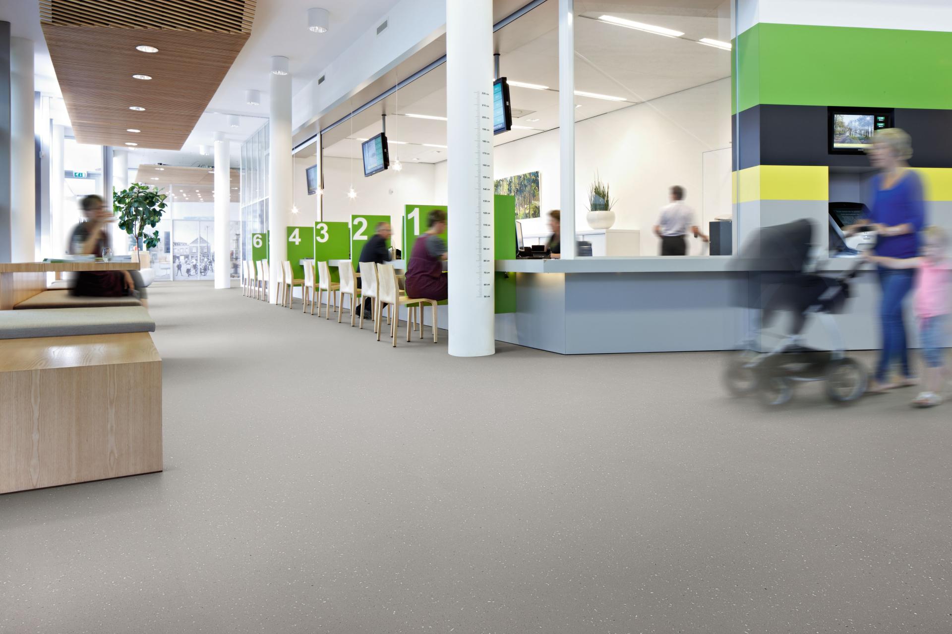 Modern interior space featuring Forbo's adhesive-free safety flooring, with visitors and green accent walls creating a vibrant atmosphere.