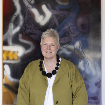 Jean Camplisson, design director at c2:concepts, poses with abstract artwork, showcasing Danish minimalism and modern design aesthetics.