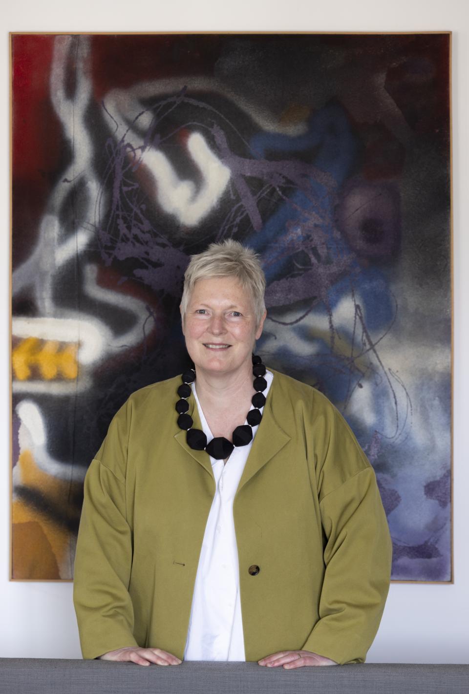 Jean Camplisson, design director at c2:concepts, poses with abstract artwork, showcasing Danish minimalism and modern design aesthetics.