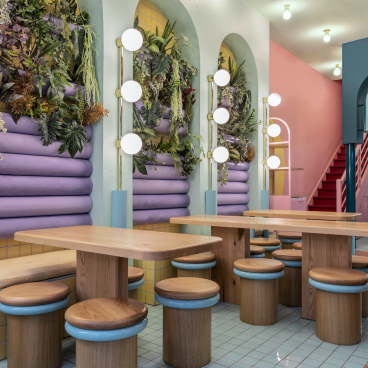 Vibrant interior of Piada’s Lyon shop featuring pastel colors, wooden furniture, and lush greenery for a fresh dining experience.