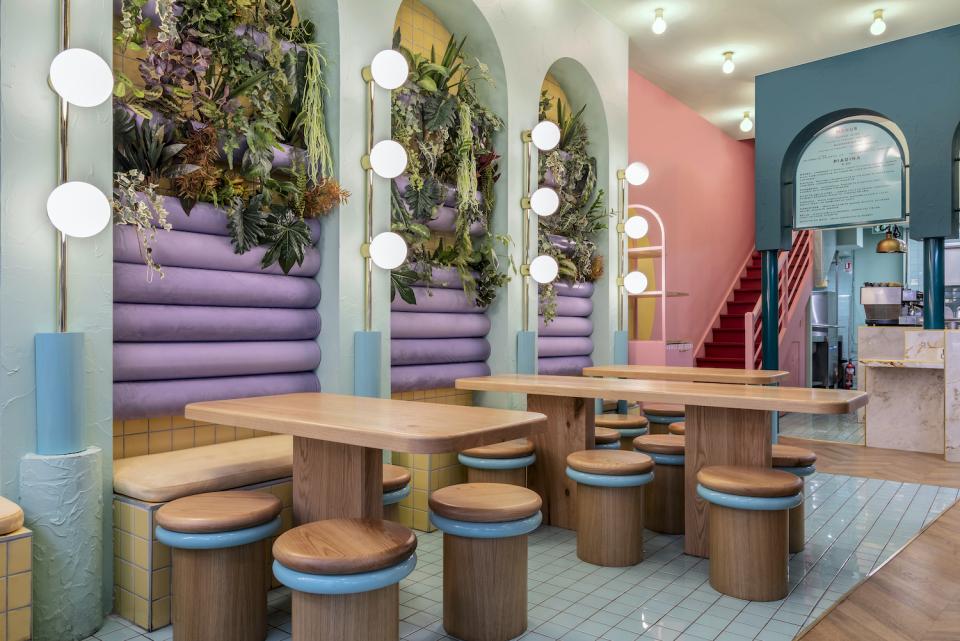Vibrant interior of Piada’s Lyon shop featuring pastel colors, wooden furniture, and lush greenery for a fresh dining experience.