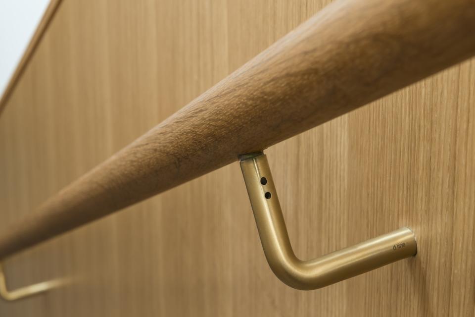 Sustainable design elements of Cambridge Central Mosque featuring a wooden handrail and gold fixtures against a wooden backdrop.