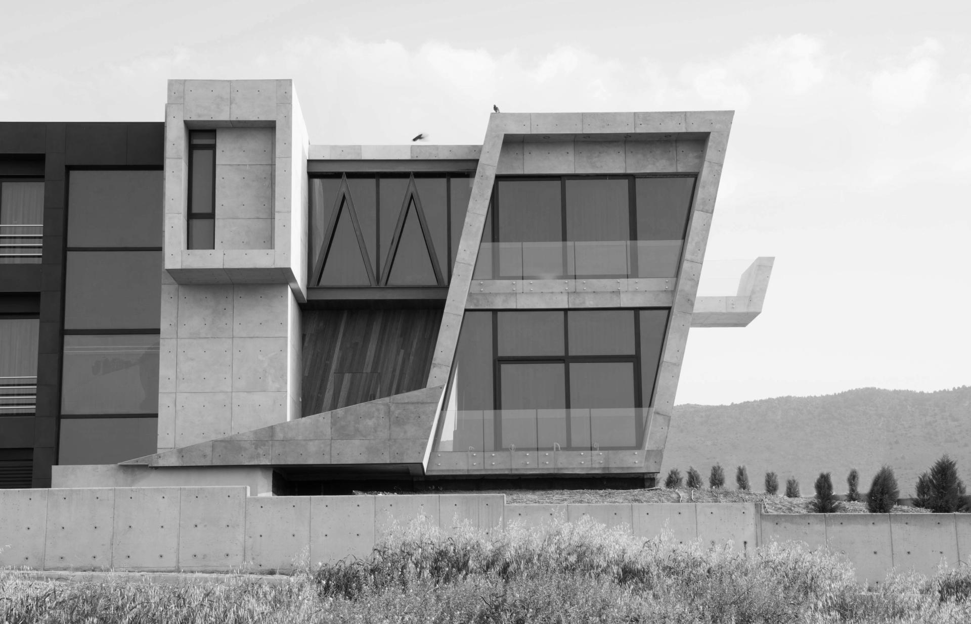 Modern architectural design featuring a striking angular building with large glass windows and concrete elements.