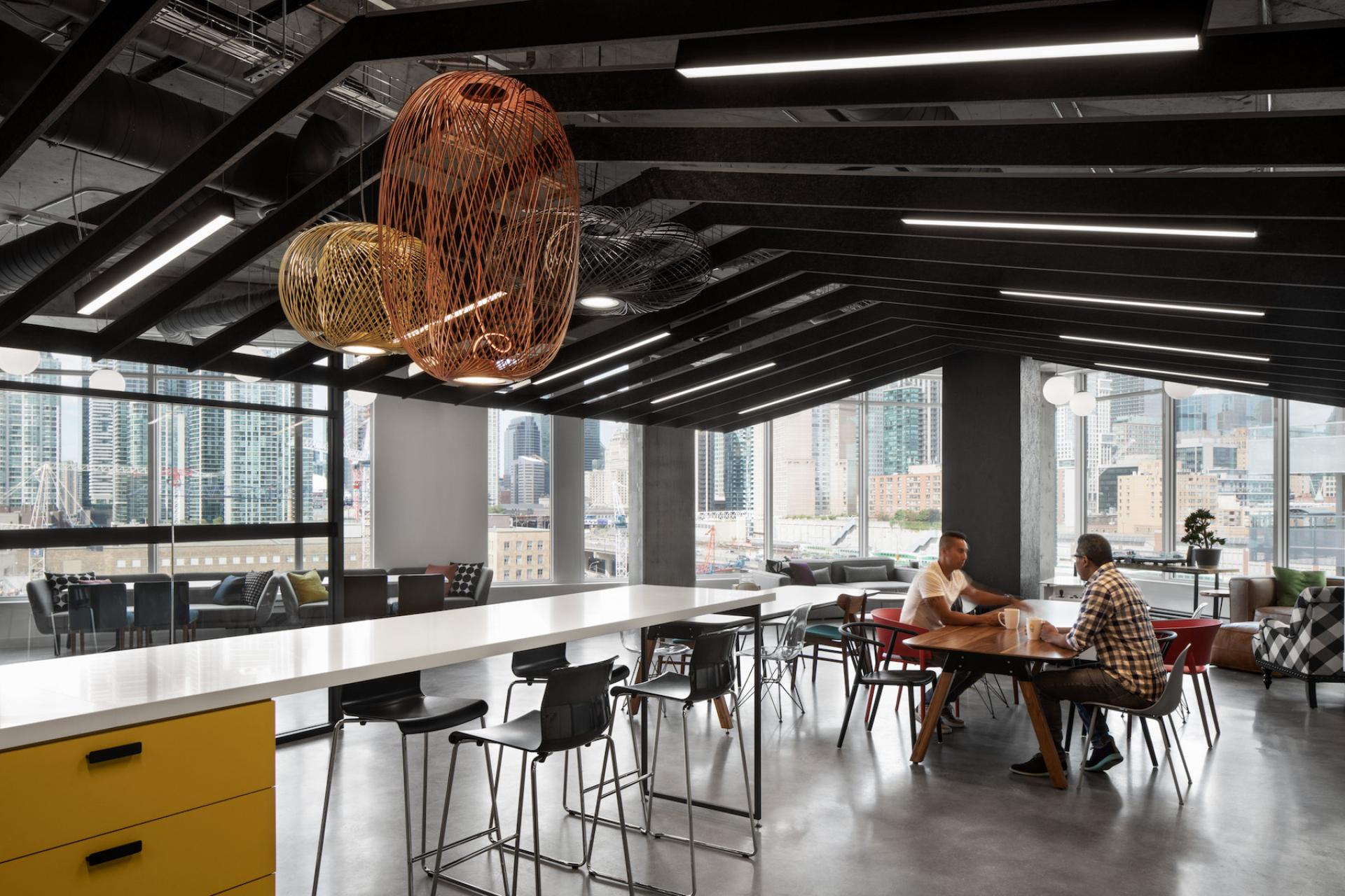 Modern workplace design featuring two professionals engaged in discussion at a stylish wooden table against a city view.