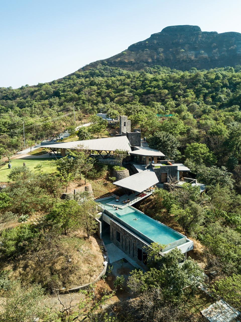Stunning aerial view of a modern villa surrounded by lush greenery and featuring a serene swimming pool.