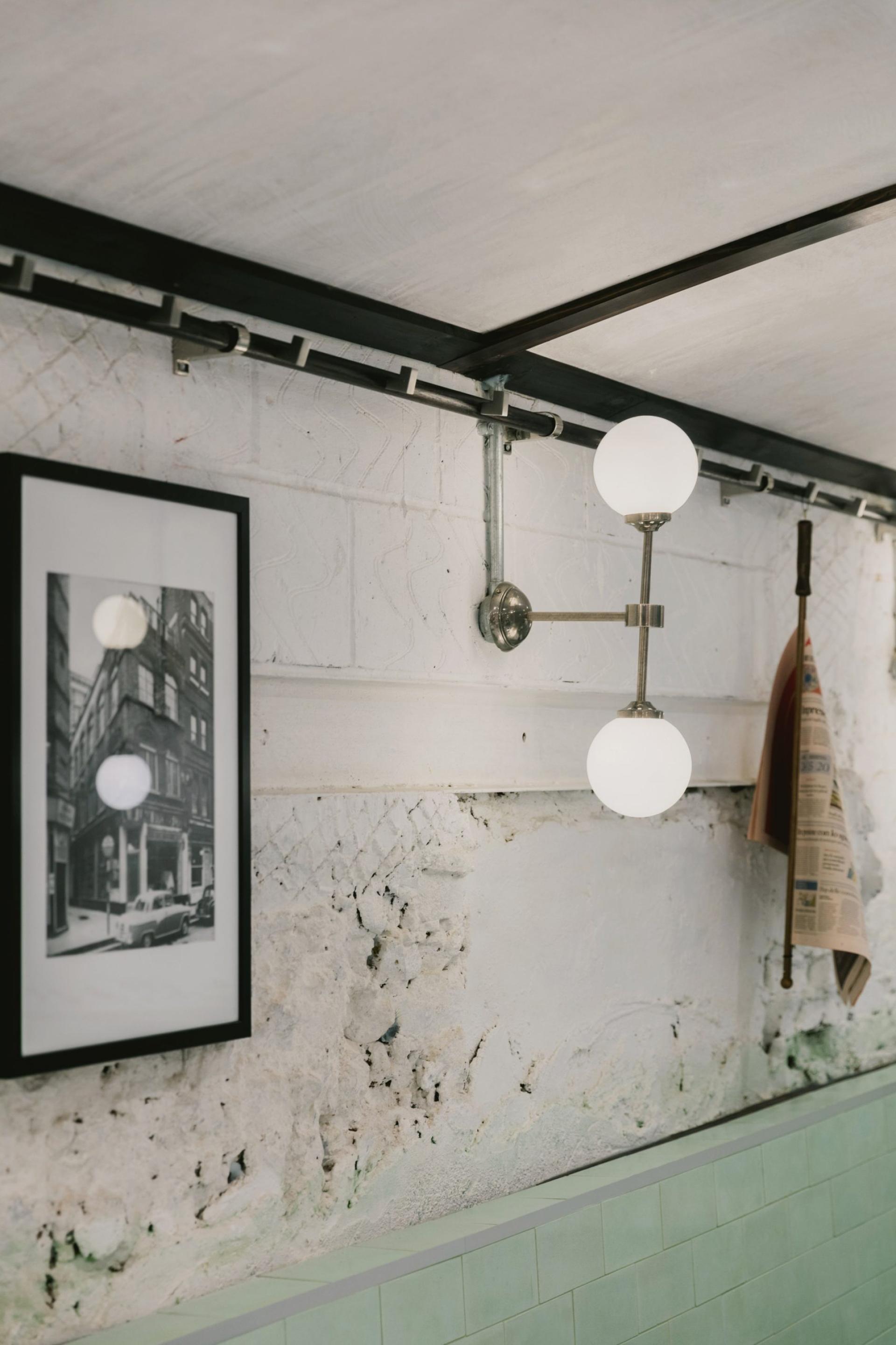 Art Deco-inspired interior featuring green and white tiles, vintage lighting, and framed historical photo in an Italian restaurant.