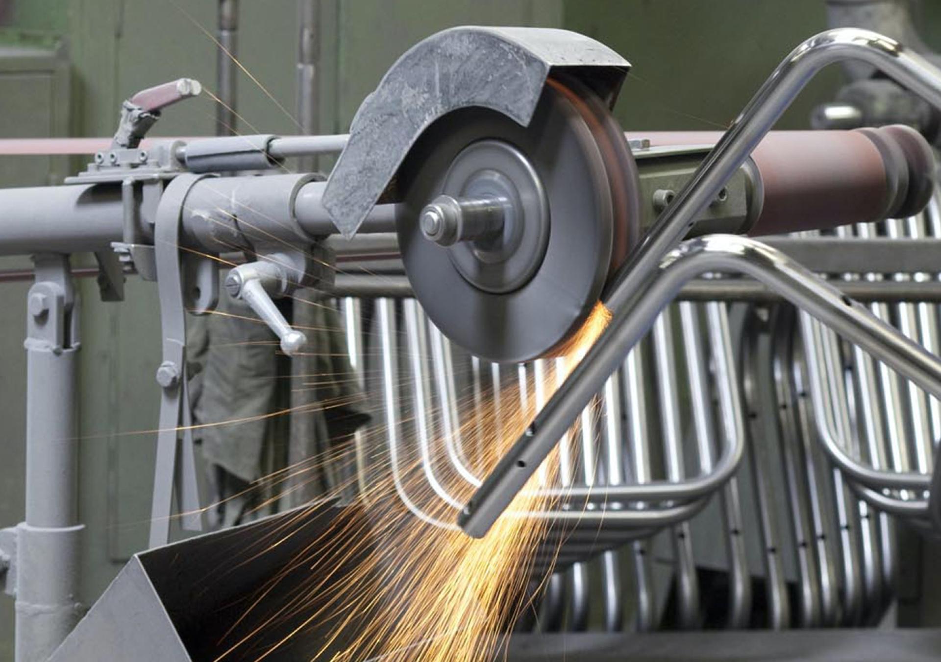 Sparks fly from a metal grinding machine in Thonet's production facility, emphasizing innovative manufacturing processes in Germany.