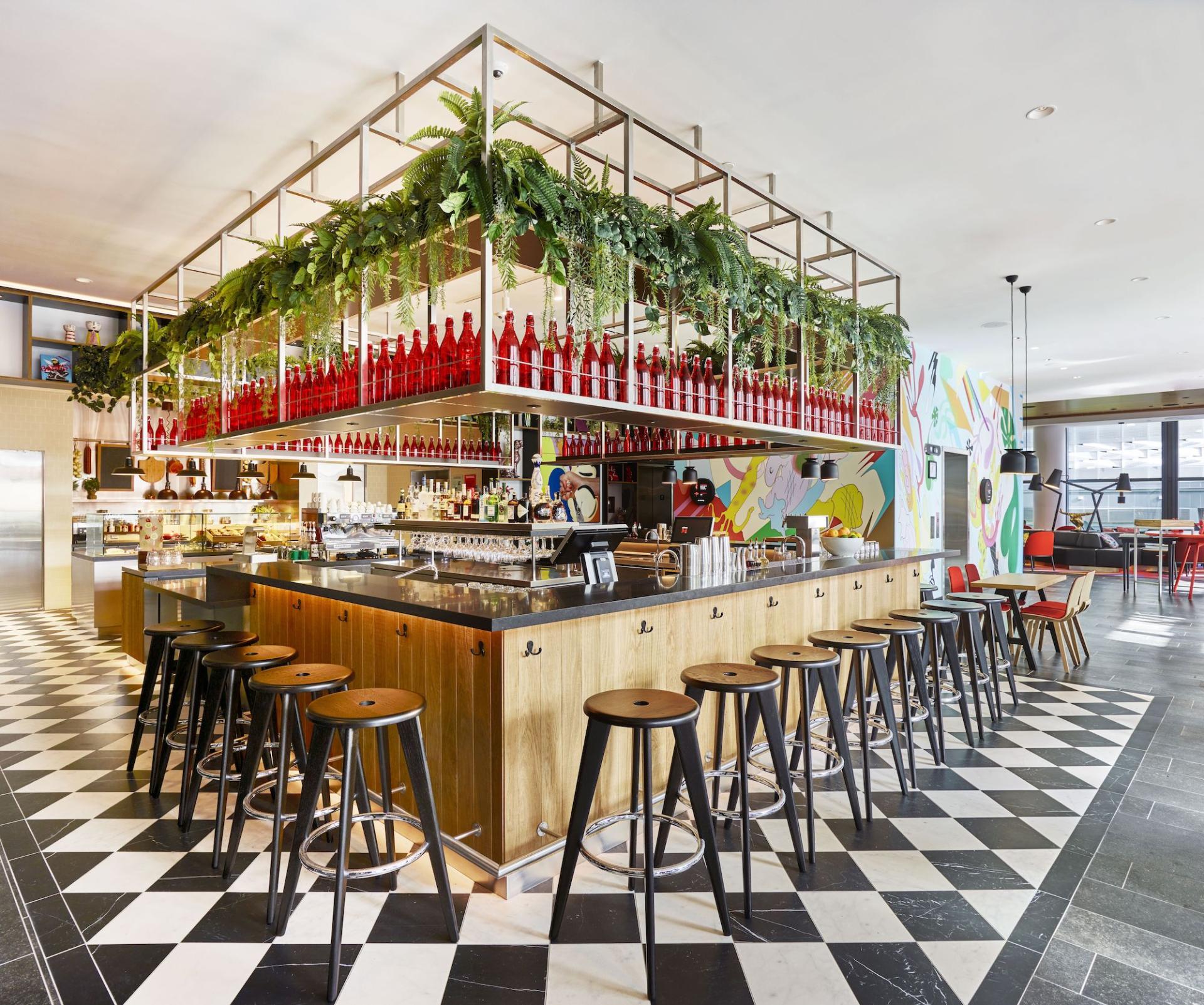 Modern hotel bar at citizenM Miami featuring stylish seating, vibrant decor, and a lush, green aesthetic.