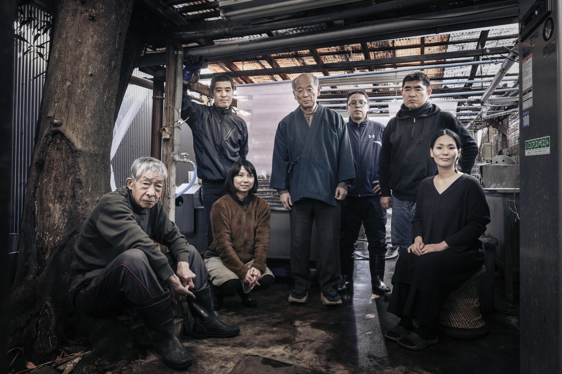 Group of artisans specializing in traditional Japanese natural dyeing techniques, showcasing their craft in a workshop setting.