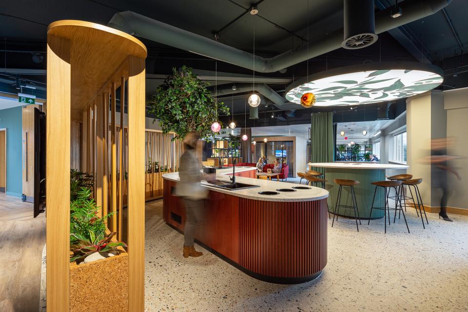 Modern workspace interior of PZ Cussons headquarters featuring a stylish bar area, greenery, and collaborative seating spaces.