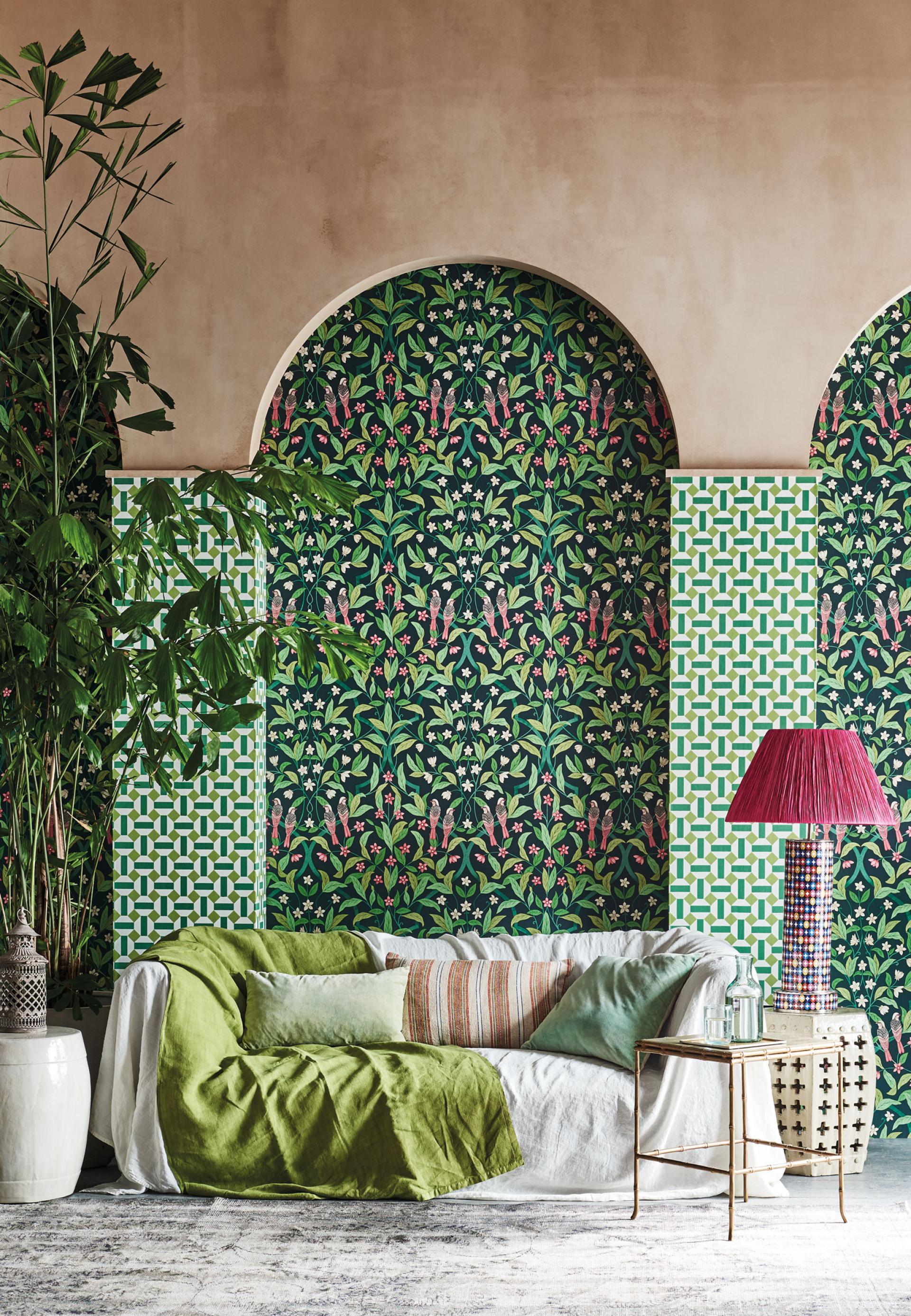 A vibrant living room featuring Cole & Son's Seville wallpaper, lush plants, and stylish decor elements.