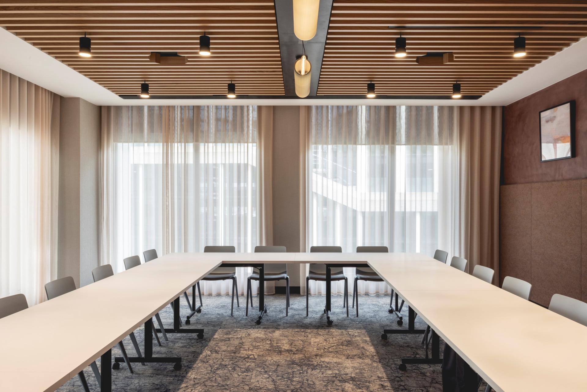 Brightly lit conference room with Art Deco-inspired design, featuring a long table and elegant curtains.