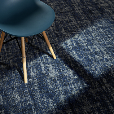Stylish blue and beige patina carpet with a mid-century chair, showcasing Newhey Carpets' innovative textile design for hospitality spaces.