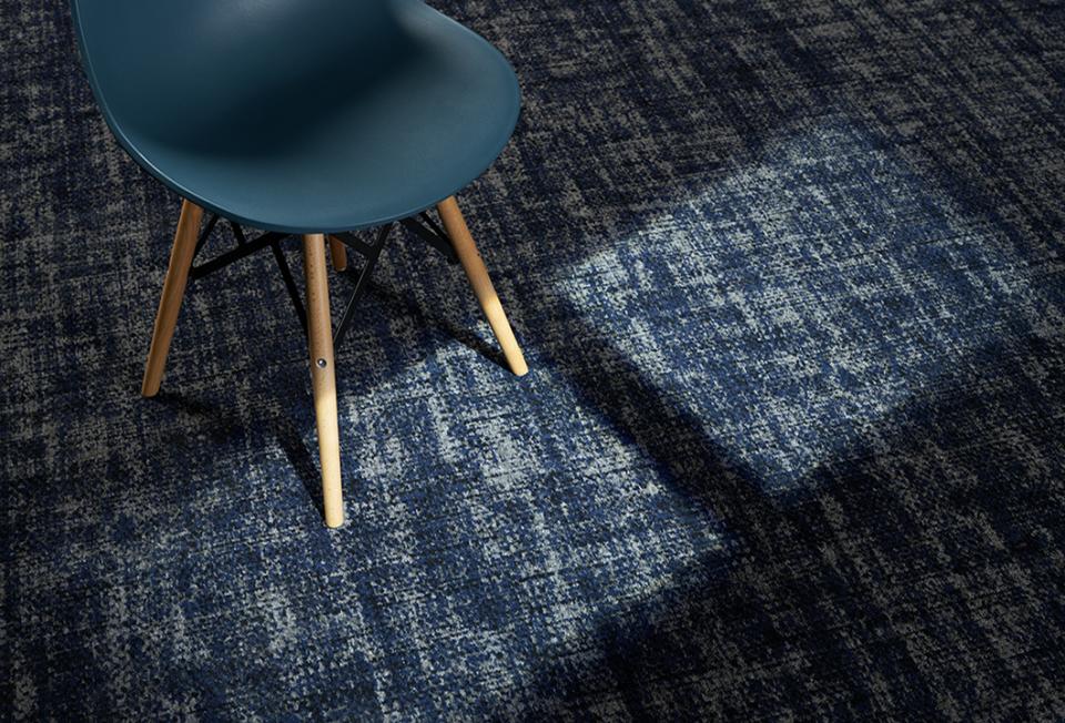 Stylish blue and beige patina carpet with a mid-century chair, showcasing Newhey Carpets' innovative textile design for hospitality spaces.