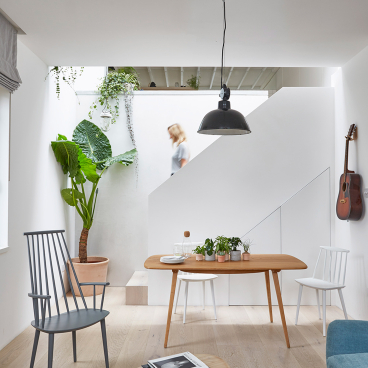 Bright and airy interior of a revamped mews house, featuring natural materials, plants, and modern furniture design.