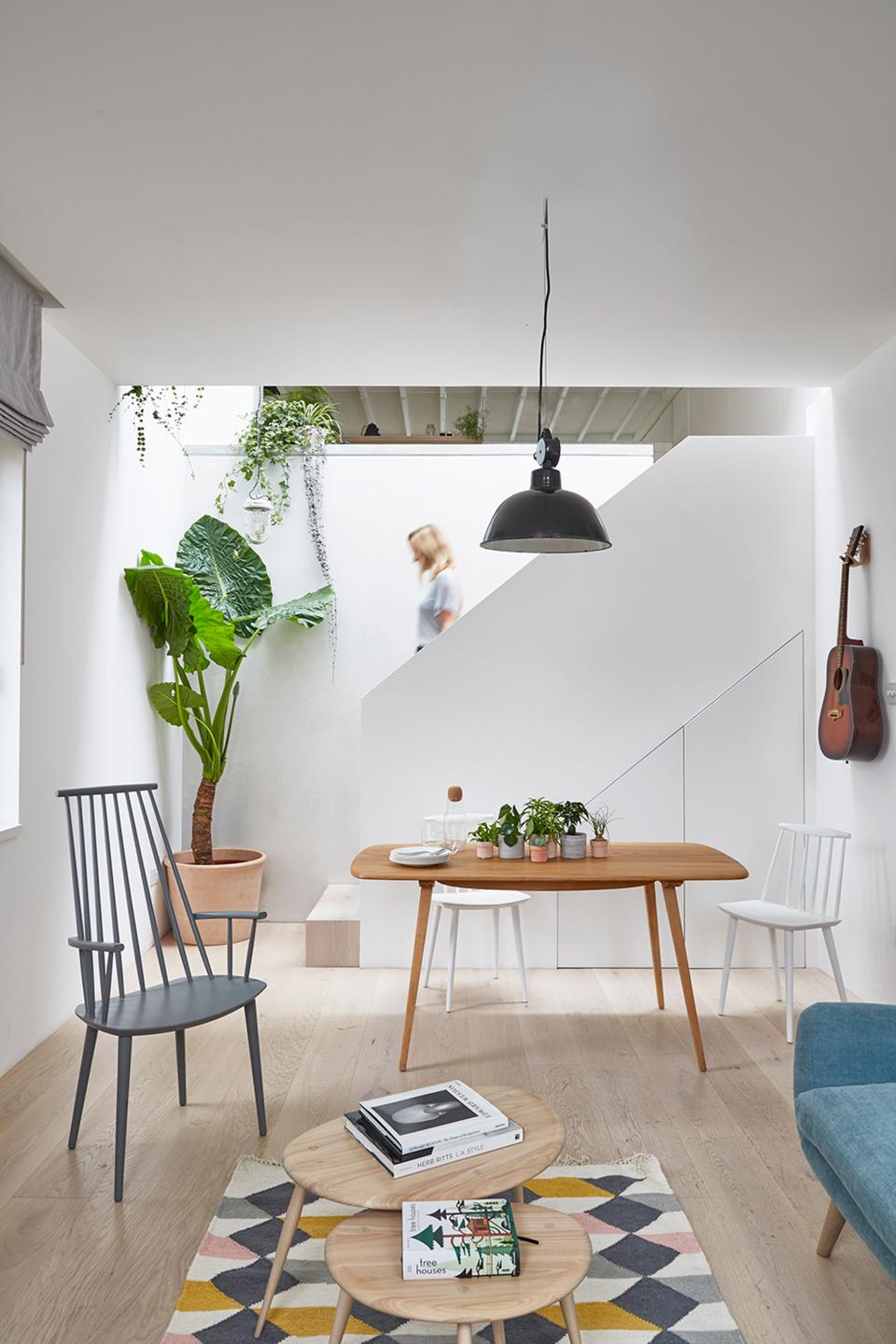 Bright and airy interior of a revamped mews house, featuring natural materials, plants, and modern furniture design.