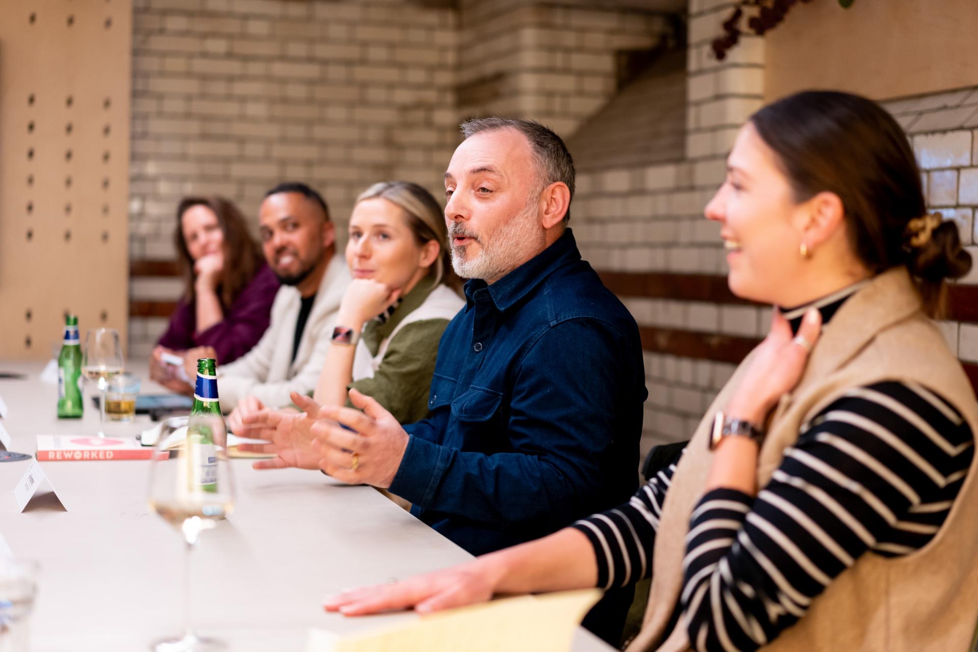 Diverse group of professionals engaged in discussion at a roundtable, focusing on EDI culture and collaboration.