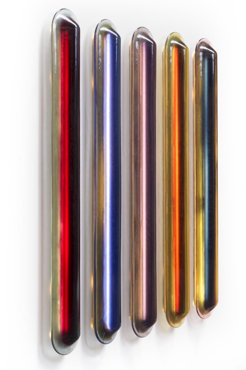 Colorful glass tubes displayed on a wall, showcasing unique designs from independent designers at the London Design Fair.