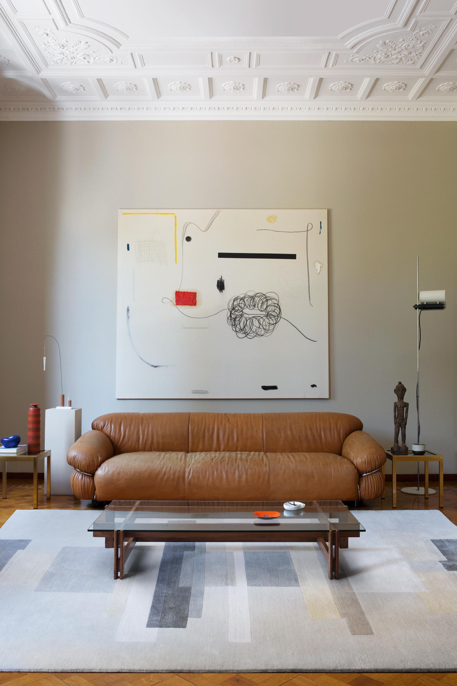 Contemporary living room featuring Jonathan Saunders' artwork, a brown leather sofa, and a geometric rug reflecting vibrant color perception.