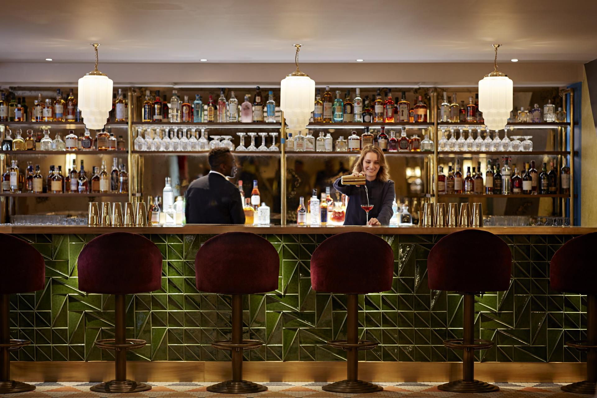Stylish bar interior at The Conduit Members Club, featuring vibrant cocktails and unique Scandinavian-inspired design elements.
