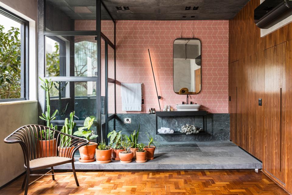 Modern bathroom design featuring natural elements, greenery, and pink geometric tiles, highlighting Apto Paulista's harmonious aesthetic.
